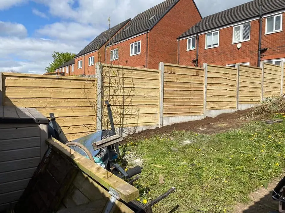 New feather-edge timber fence panels on concrete posts along a sloped garden boundary